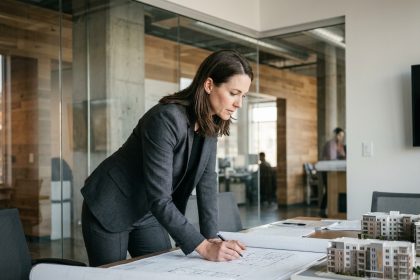 Chef de projet immobilier femme examinant des plans architecturaux dans un bureau moderne avec maquettes de bâtiments