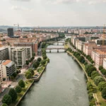 Vue aérienne panoramique de Toulouse avec le fleuve Garonne, les bâtiments résidentiels modernes et l'architecture historique en brique rose, illustrant le marché immobilier en Haute-Garonne