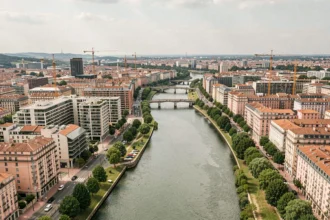 Vue aérienne panoramique de Toulouse avec le fleuve Garonne, les bâtiments résidentiels modernes et l'architecture historique en brique rose, illustrant le marché immobilier en Haute-Garonne